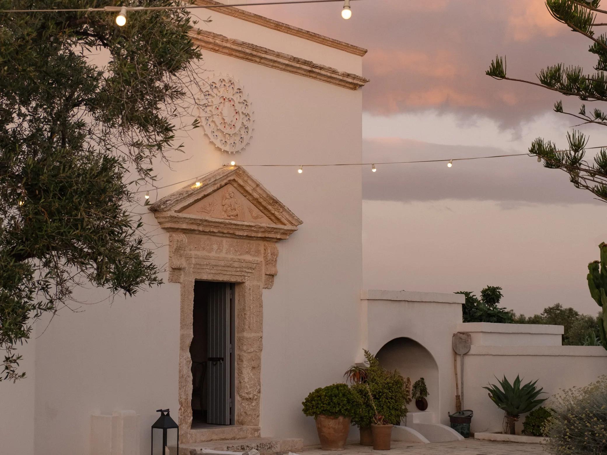 The lit chapel courtyard at Masseria Calderisi in Puglia at dusk, judgement in luxury hotel operations