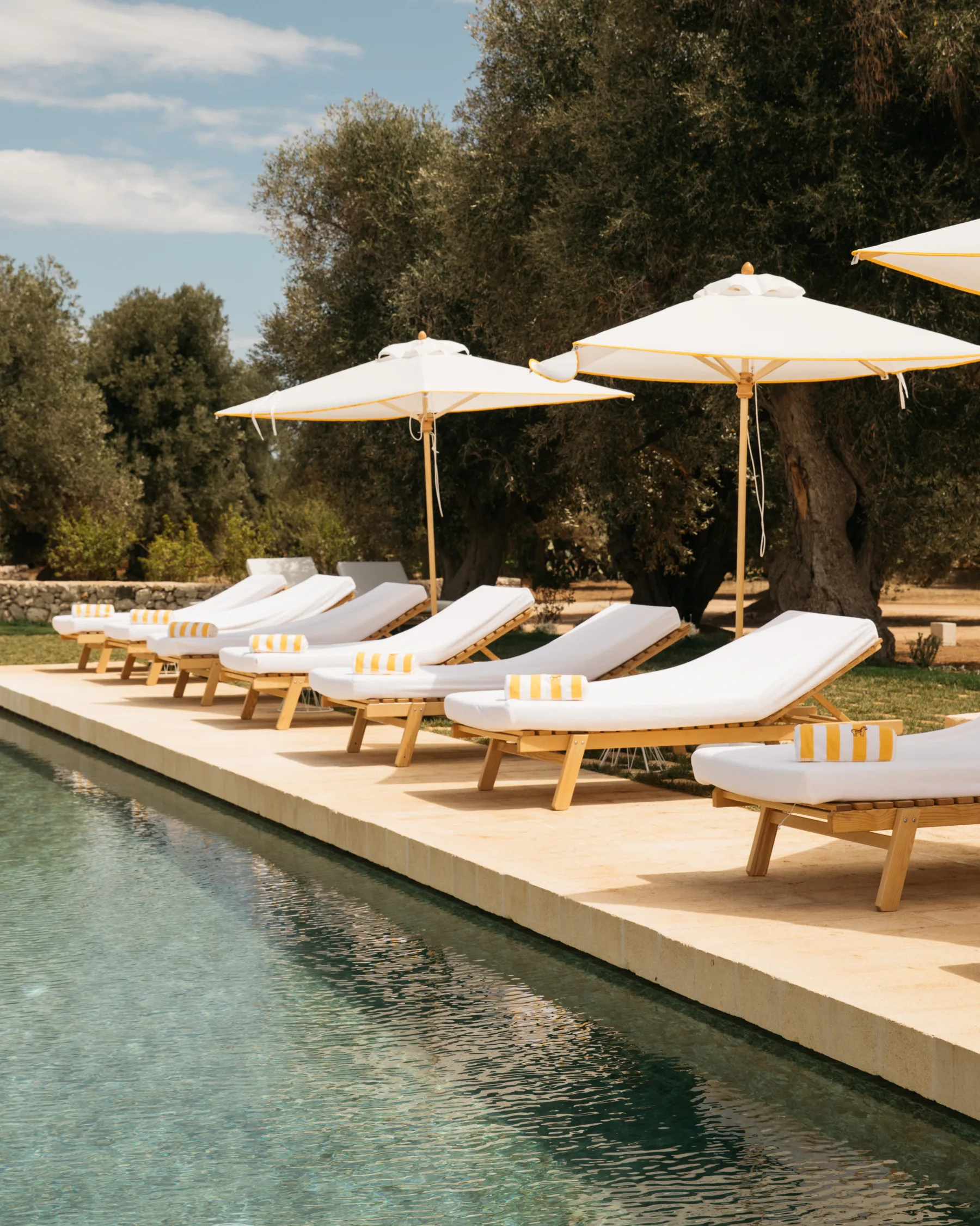 Poolside loungers and parasols set in line at Masseria Calderisi, clarity in luxury hospitality